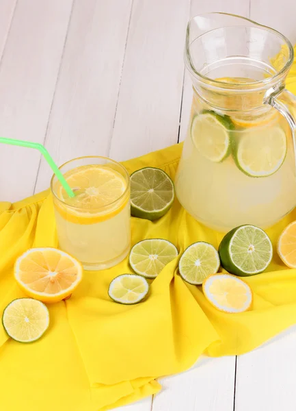 Limonada cítrica en vidrio y jarra de cítricos alrededor en tela amarilla en w — Foto de Stock