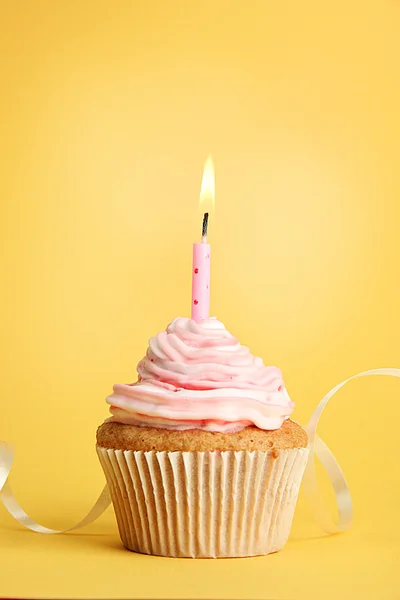 Tasty birthday cupcake with candle, on yellow background Stock Image