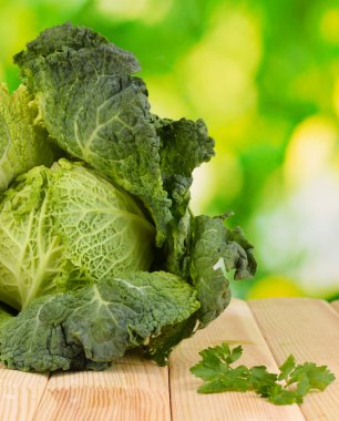 Fresh savoy cabbage on wooden table on natural background