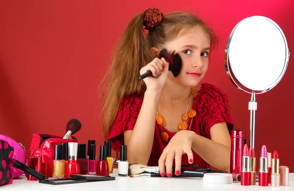 Liten flicka i sin mors klänning med make up penslar — Stockfoto