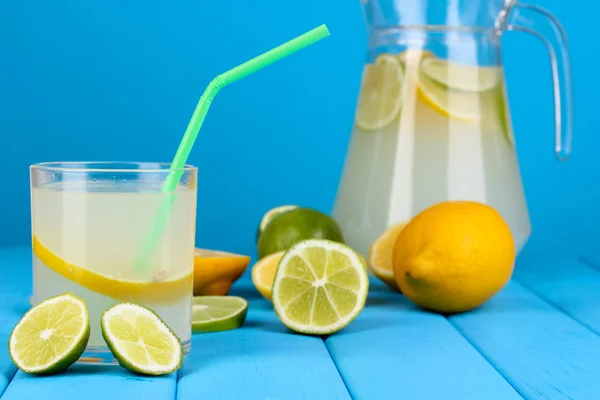 Цитрусовый лимонад в кувшине и стакан цитрусовых вокруг на деревянном столе на bl — стоковое фото