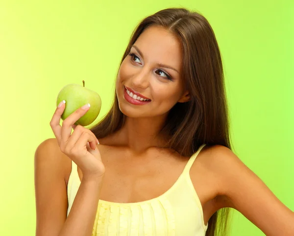 Hermosa joven con manzana verde, sobre fondo verde —  Fotos de Stock