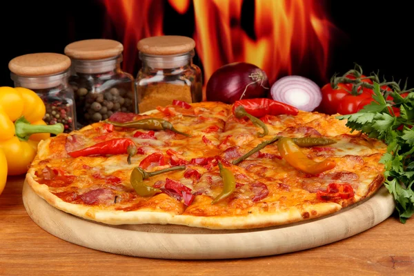 Leckere Pfefferoni-Pizza mit Gemüse auf Holzbrett auf Flammenhintergrund — Stockfoto