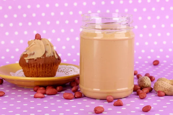 Leckere Erdnussbutter mit Kuchen auf lila Hintergrund mit Tupfen — Stockfoto