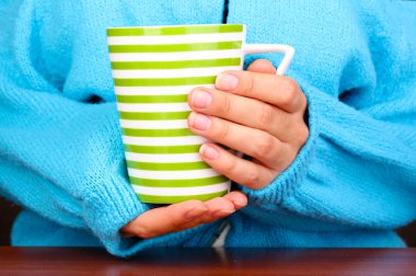 yakın çekim sıcak bir fincan tutan eller iç