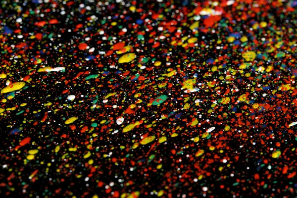 Bright splashes of paint on black background close-up — Stock Photo, Image