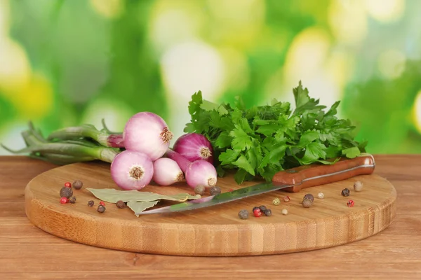 Cipolla giovane sul tagliere con verde, pepe e coltello su tavola di legno — Foto Stock