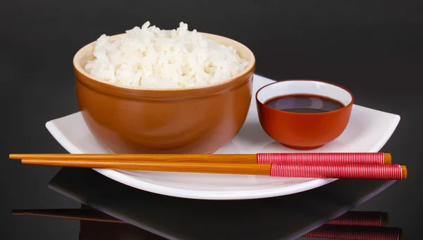 Ciotola di riso e bacchette su piatto su fondo grigio — Foto Stock