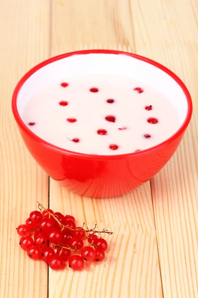 Йогурт с красной смородиной на деревянном столе — стоковое фото