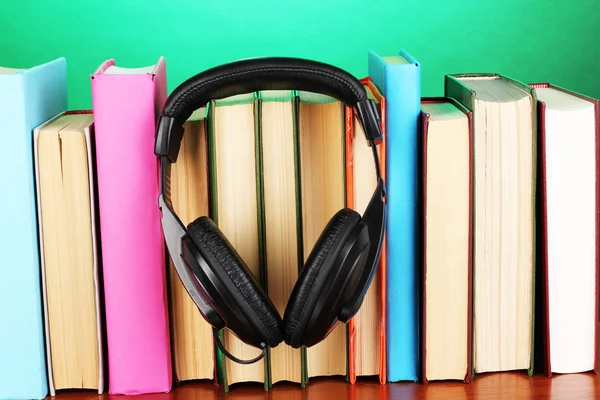 Auriculares en libros sobre mesa de madera sobre fondo turquesa —  Fotos de Stock