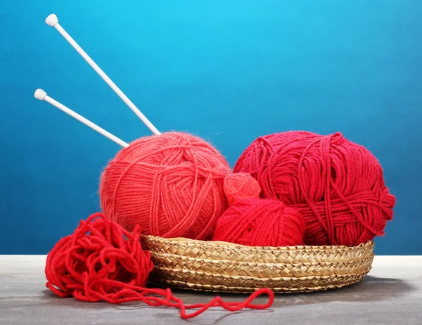 Basketon 青い背景に木製のテーブルの上に赤の編物展糸 — ストック写真