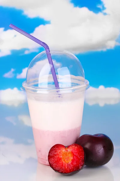 Delicious milk shake with fruit on table on sky background — Stock Photo, Image