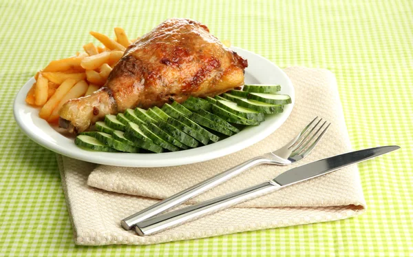 Roast chicken with french fries and cucumbers, on green table cloth — Stock Photo, Image