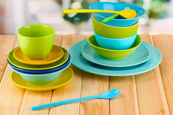 Colorful tableware on wooden table on window background — Stock Photo, Image