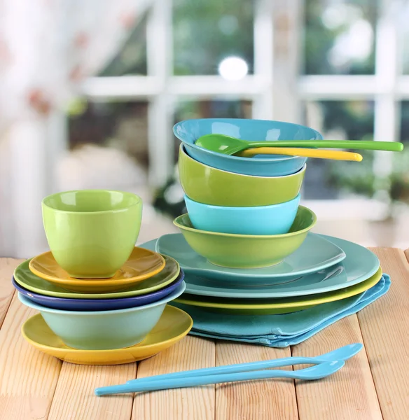 Kleurrijke tafelgerei op houten tafel op achtergrond van venster — Stockfoto