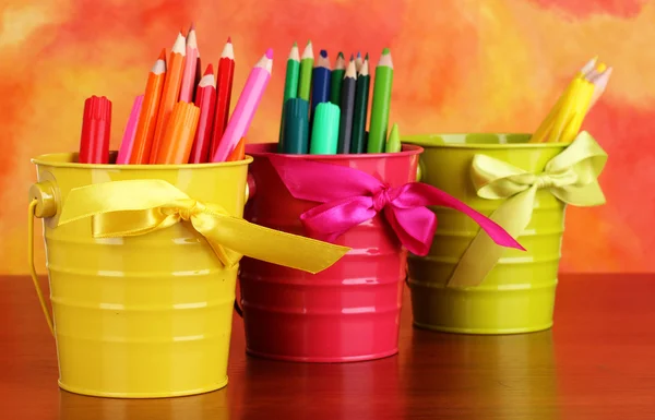 Colorful pencils and felt-tip pens in pails on color background — Stock Photo, Image