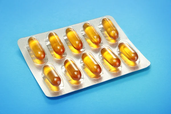 Capsules packed in blisters, on blue background — Stock Photo, Image