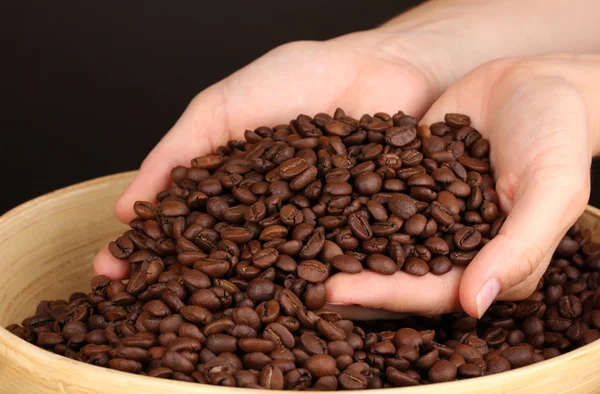 Kaffeebohnen in der Hand auf dunklem Hintergrund — Stockfoto