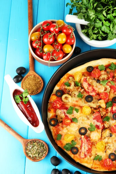 Kleurrijke samenstelling van heerlijke pizza, groenten en specerijen op blauwe hout — Stockfoto