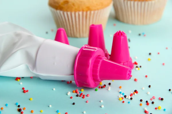 Confectionery bag with replaceable nozzles and cake, on blue background — Stock Photo, Image