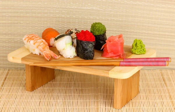 Délicieux sushi servi sur planche de bois sur tapis de bambou — Photo