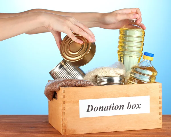 Donation box with food on blue background close-up — Stock Photo, Image