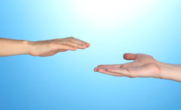 Women's hand goes to the man's hand on blue background Stock Photo