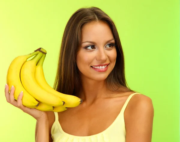 Hermosa joven con plátanos, sobre fondo verde — Foto de Stock