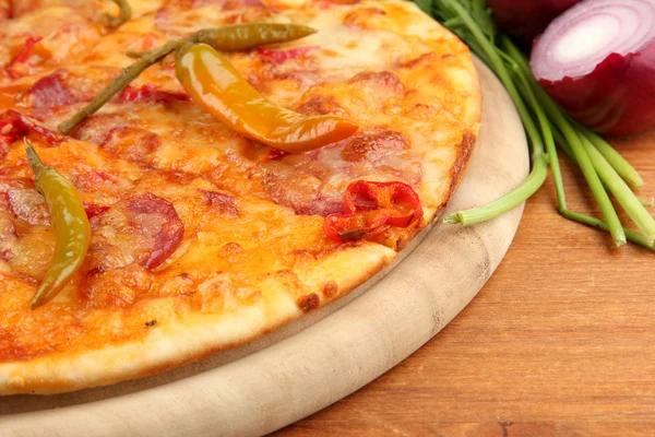 Tasty pepperoni pizza on wooden board on wooden background — Stock Photo, Image