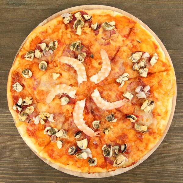 Deliziosa pizza con frutti di mare su basamento su sfondo di legno — Foto Stock