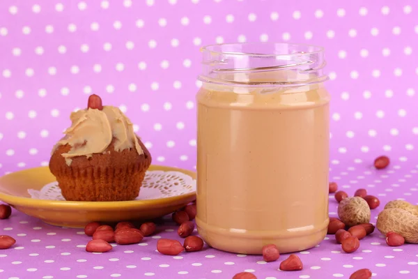 Leckere Erdnussbutter mit Kuchen auf lila Hintergrund mit Tupfen — Stockfoto