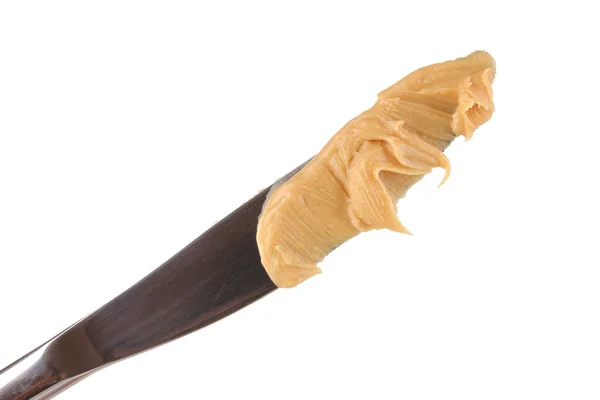 Köstliche Erdnussbutter auf Messer isoliert auf weißen Nahaufnahme — Stockfoto