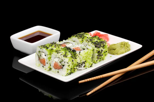 Deliciosos rollos servidos en plato blanco con palillos aislados en negro — Foto de Stock