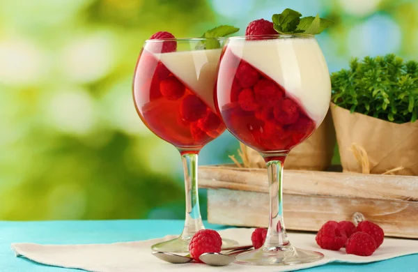 Fruchtgelee in Gläsern, Beeren und Minze auf Tisch auf grünem Hintergrund — Stockfoto