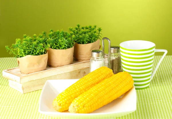 Boiled corn and flowers on a green background — Stock Photo, Image