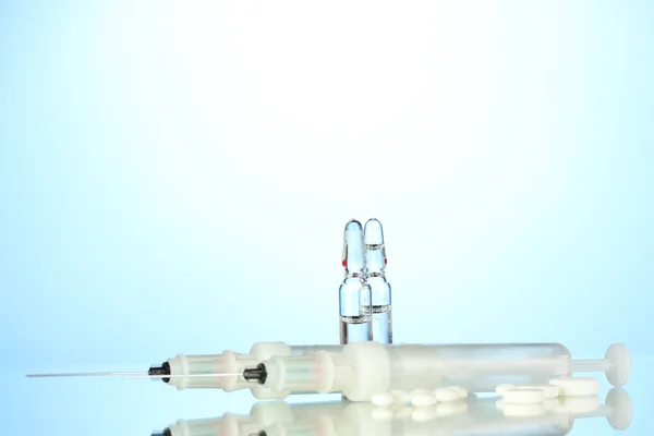 Syringes monovet, ampoules and pills on blue background — Stock Photo, Image