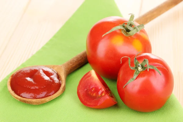 Ketchup and ripe tomatoes on wooden table — Stock Photo, Image