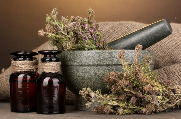 Thyme herb and mortar on wooden table on brown background — Stock Photo, Image