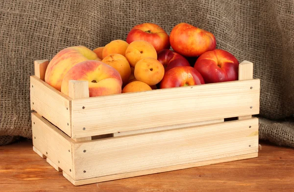 Ripe fruit in wooden box on canvas background close-up — 스톡 사진