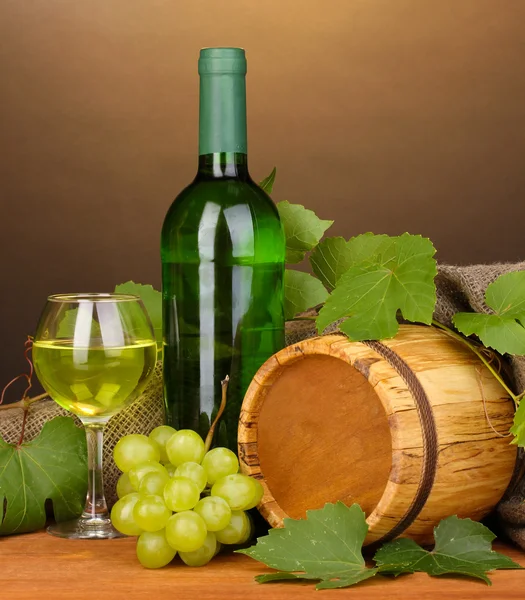 Бутылка отличного вина со стаканом и октавой на деревянном столе на коричневом бэкгро — стоковое фото