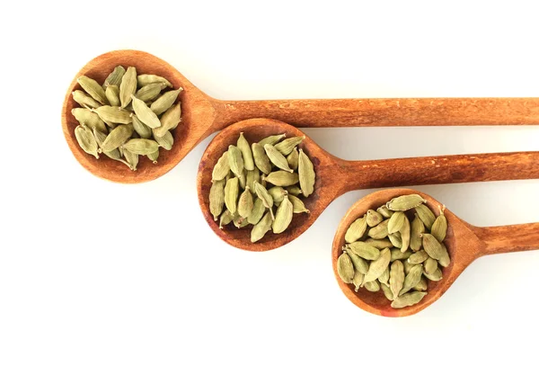 Cardamomo verde in cucchiai di legno su sfondo bianco primo piano — Foto Stock