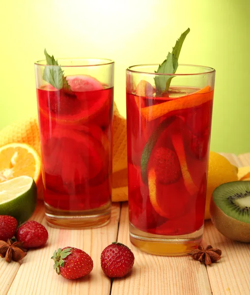 Sangria in Gläsern mit Früchten, auf Holztisch, auf grünem Hintergrund — Stockfoto