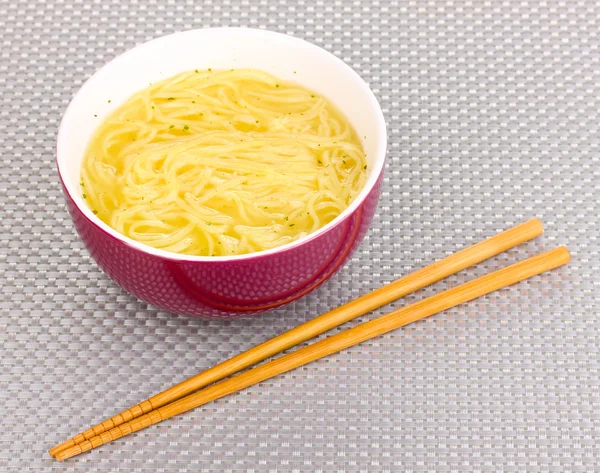 Tagliatelle asiatiche in ciotola su tappetino grigio — Foto Stock