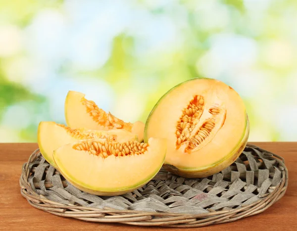 Cut melon on wicker mat on green background close-up — Stock Photo, Image