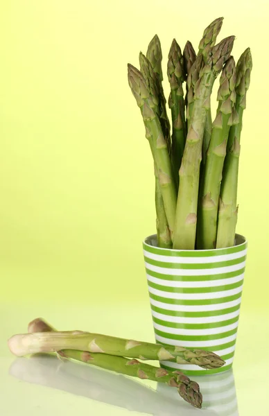 Fresh asparagus in colorful pot on green background — Stock Photo, Image