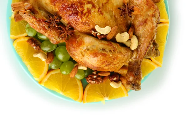 Poulet rôti entier avec des raisins, des oranges et des épices sur une assiette bleue sur du blanc — Photo