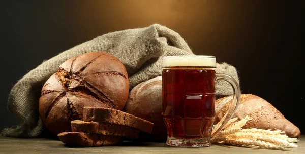 Tankard de kvass e pão de centeio com orelhas, em mesa de madeira em backgro marrom — Fotografia de Stock