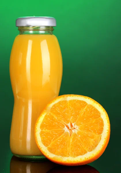 Sumo de laranja delicioso em uma garrafa e laranja ao lado dele no backgr colorido — Fotografia de Stock