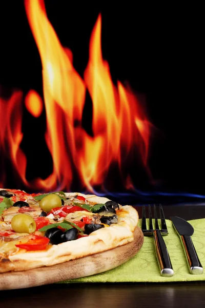 Delicioso primer plano de pizza sobre mesa de madera sobre fondo de fuego —  Fotos de Stock