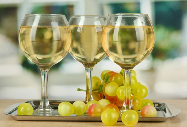 Witte wijn in glazen op salver op de achtergrond van venster — Stockfoto